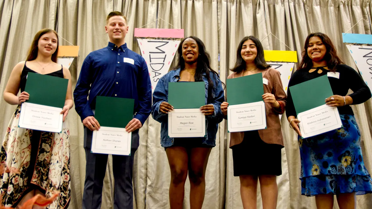 Group of five individuals holding up certificates in front of a banner