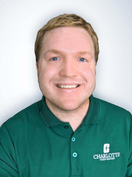 Profile photo of Joshua Wood smiling, wearing a green polo shirt with the UNC Charlotte logo