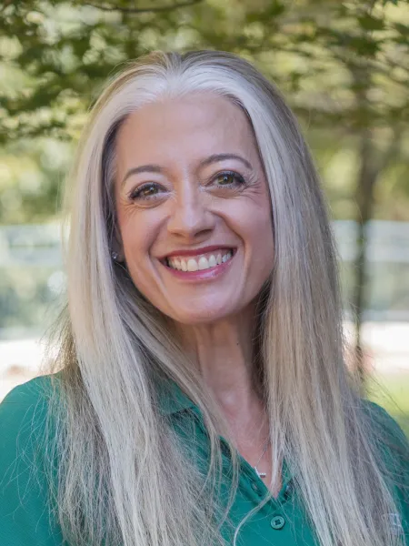 Profile photo of Kelly Merges smiling, wearing a green polo shirt with the UNC Charlotte logo