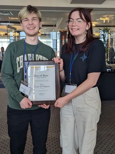 Two Charlotte students standing next to each other holding a plaque.