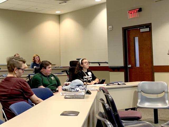 Student editor-in-chief stands in front of a lecture talking to newly recruited students.