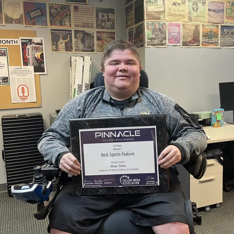 A person in a chair holding an award plaque.